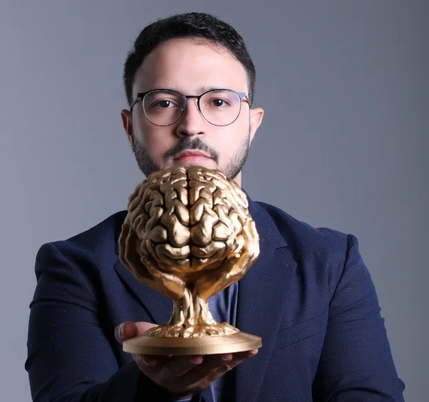 Dr. Caio Siqueira segurando uma escultura dourada de um cérebro